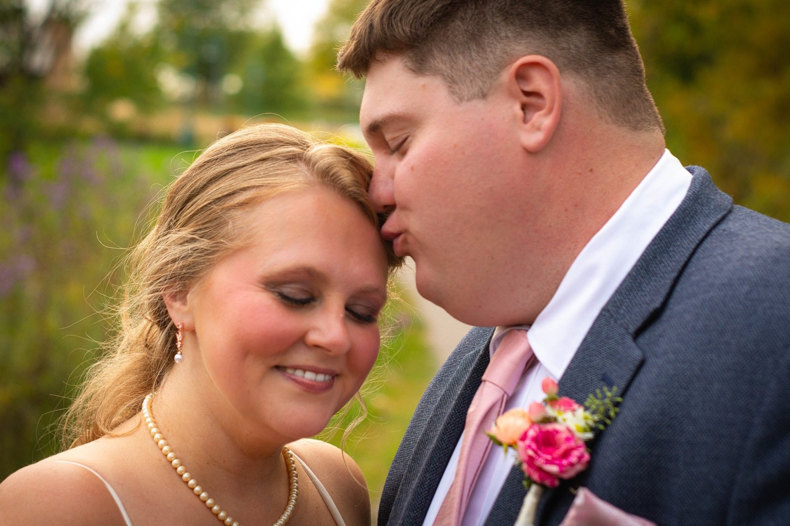 Groom kissing bride on forehead